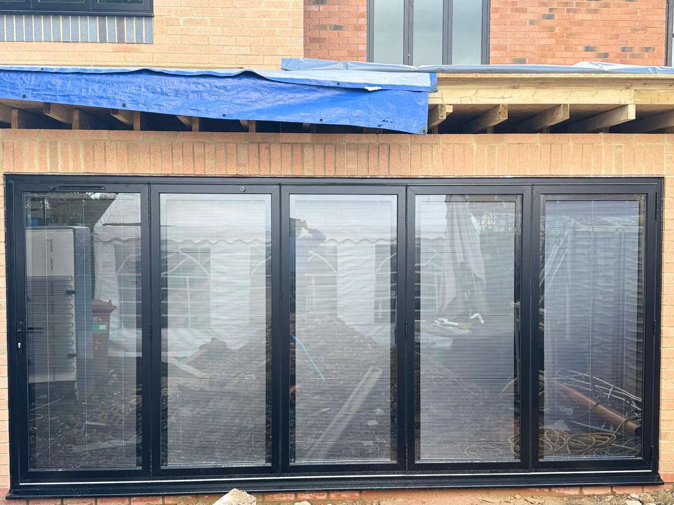 Black five-panel bifold doors installed in a building extension