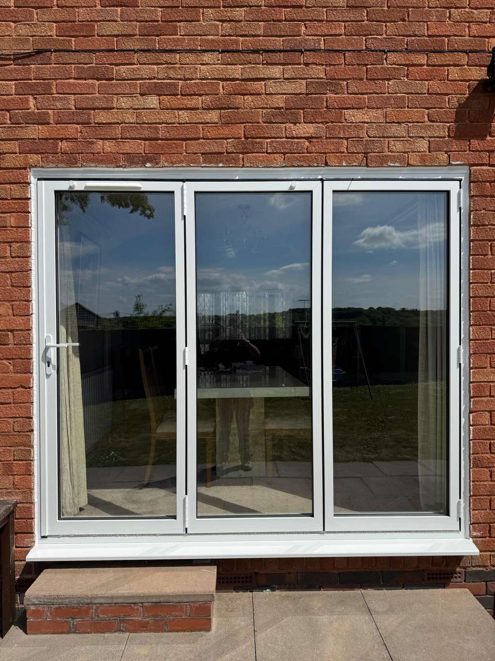 White three-panel French doors in a brick wall