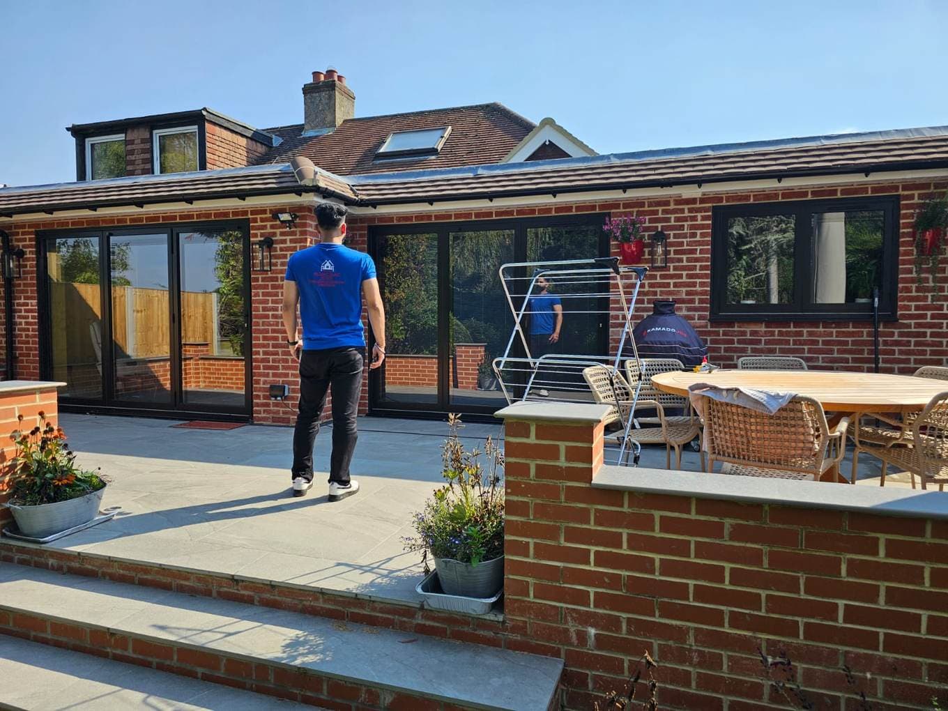 Single-storey brick extension with black sliding doors and a team member on the patio