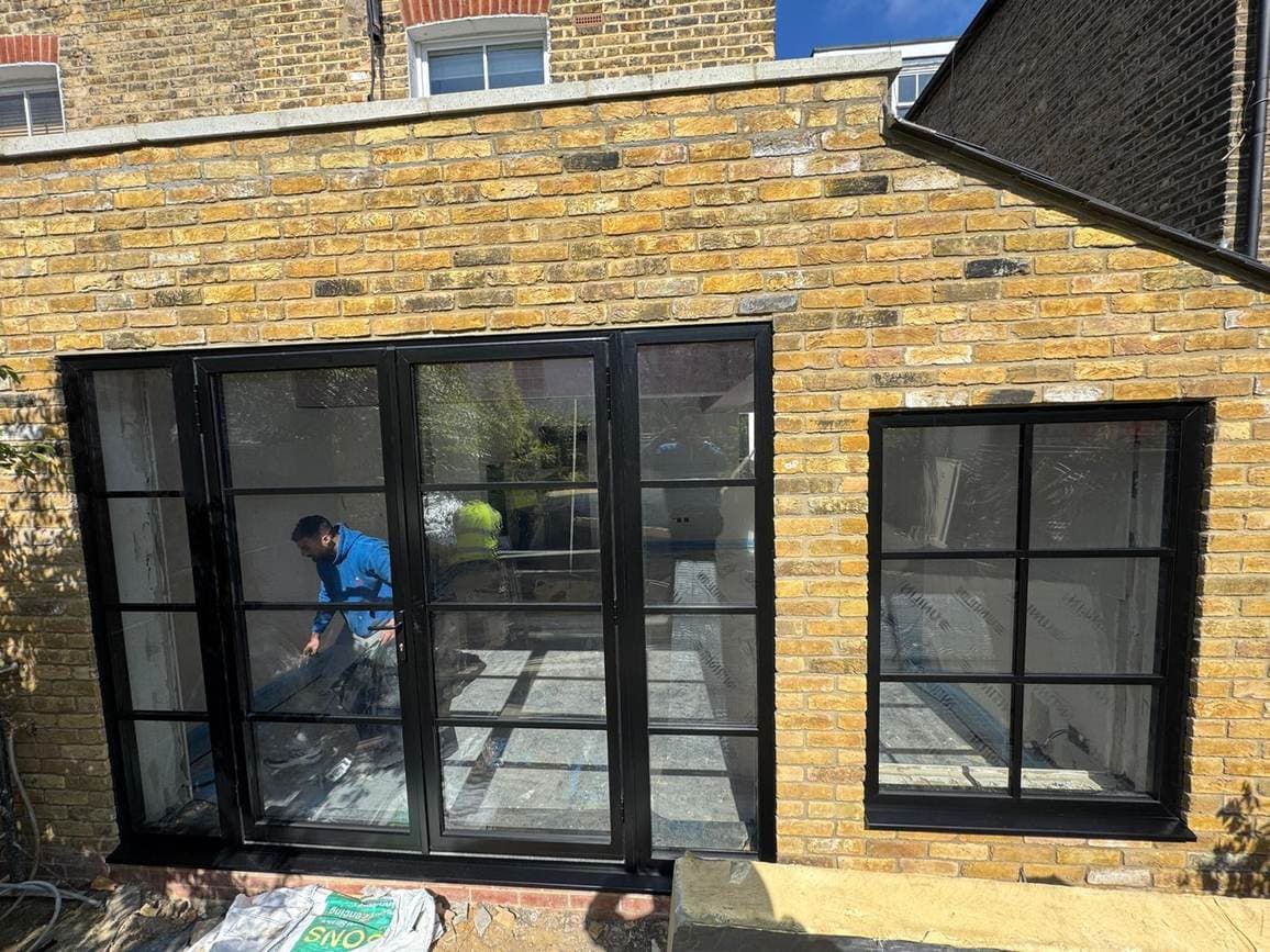 Black steel-look doors and window fitted into a yellow-brick extension