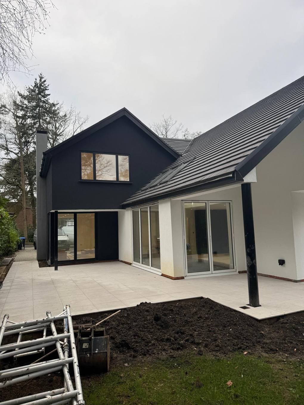 Dark-clad house with glazed doors onto a new patio
