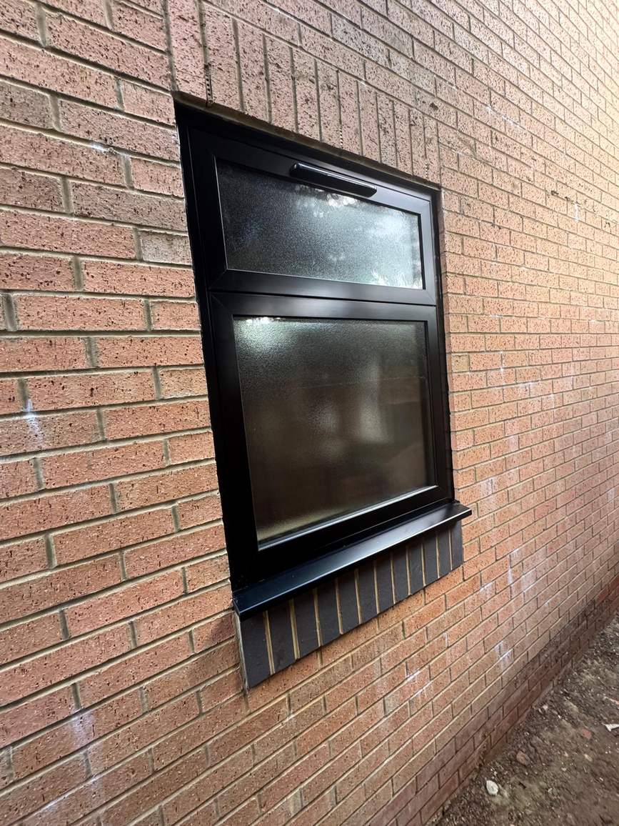 Black window fitted in a red-brick wall