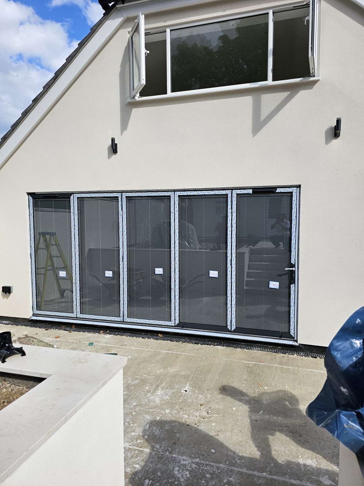 Bifold doors under a gable window on a white-rendered house