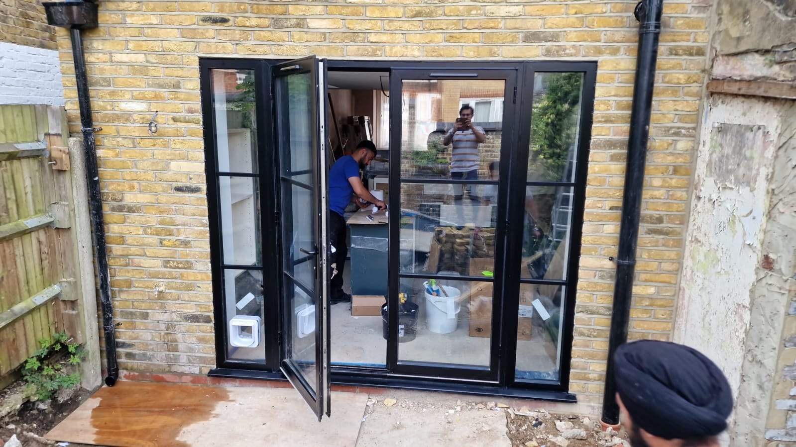 Black steel-look French doors open in a brick rear wall