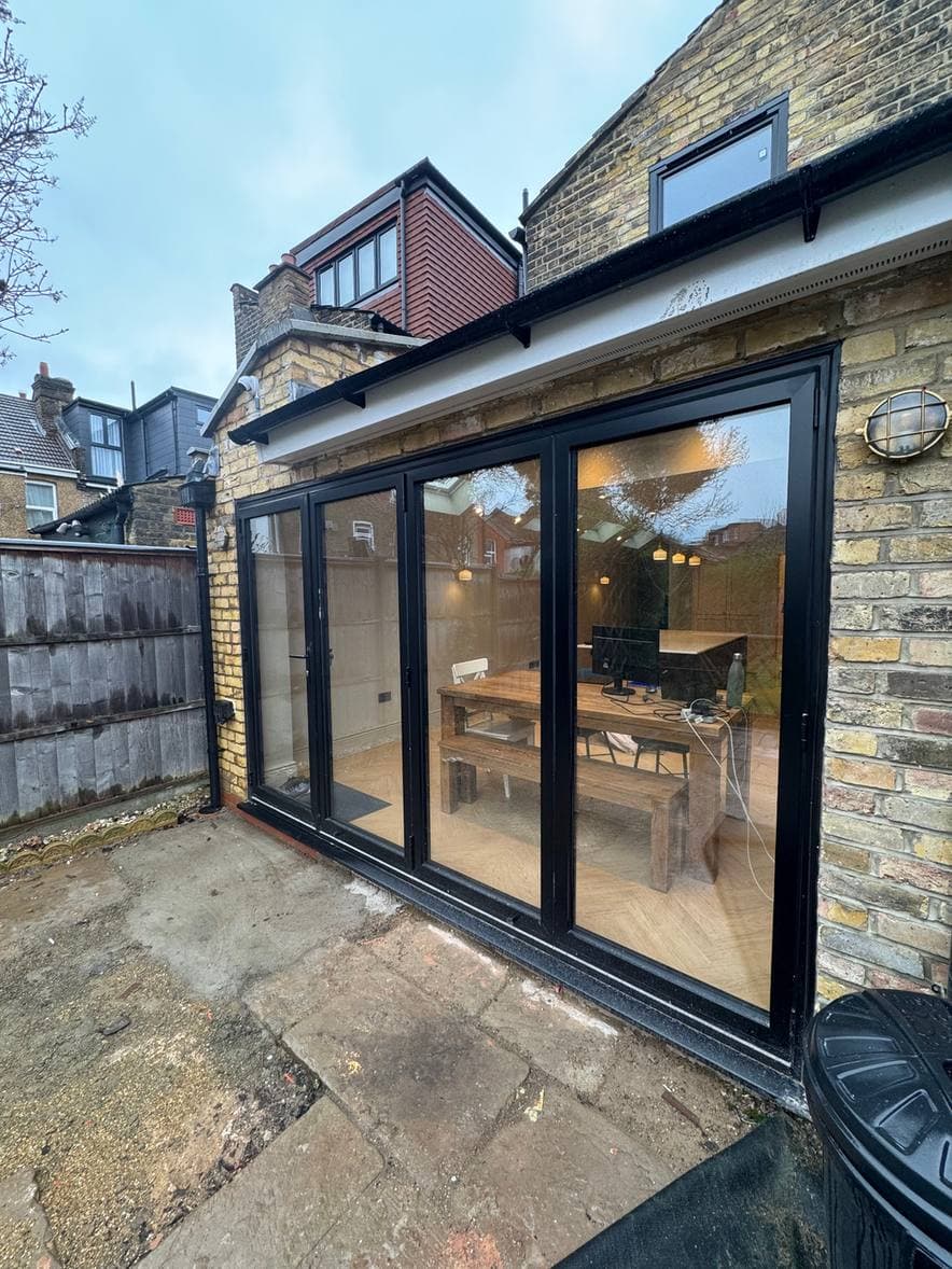 Black aluminium sliding doors across the back of a brick house