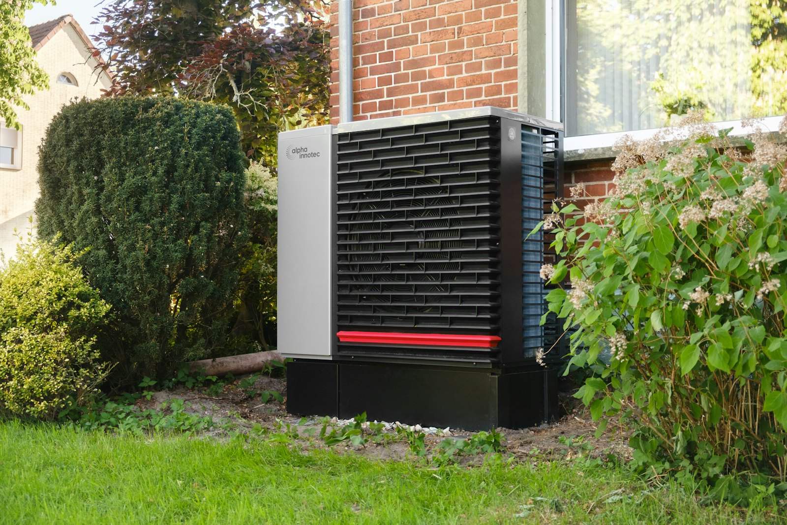 Heat pump unit beside a brick house in a garden