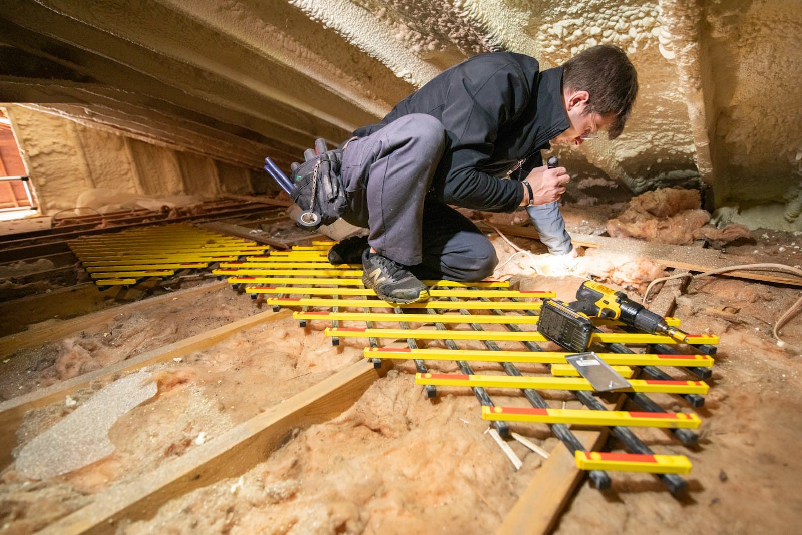 Installer fitting raised loft boarding over insulation between roof joists