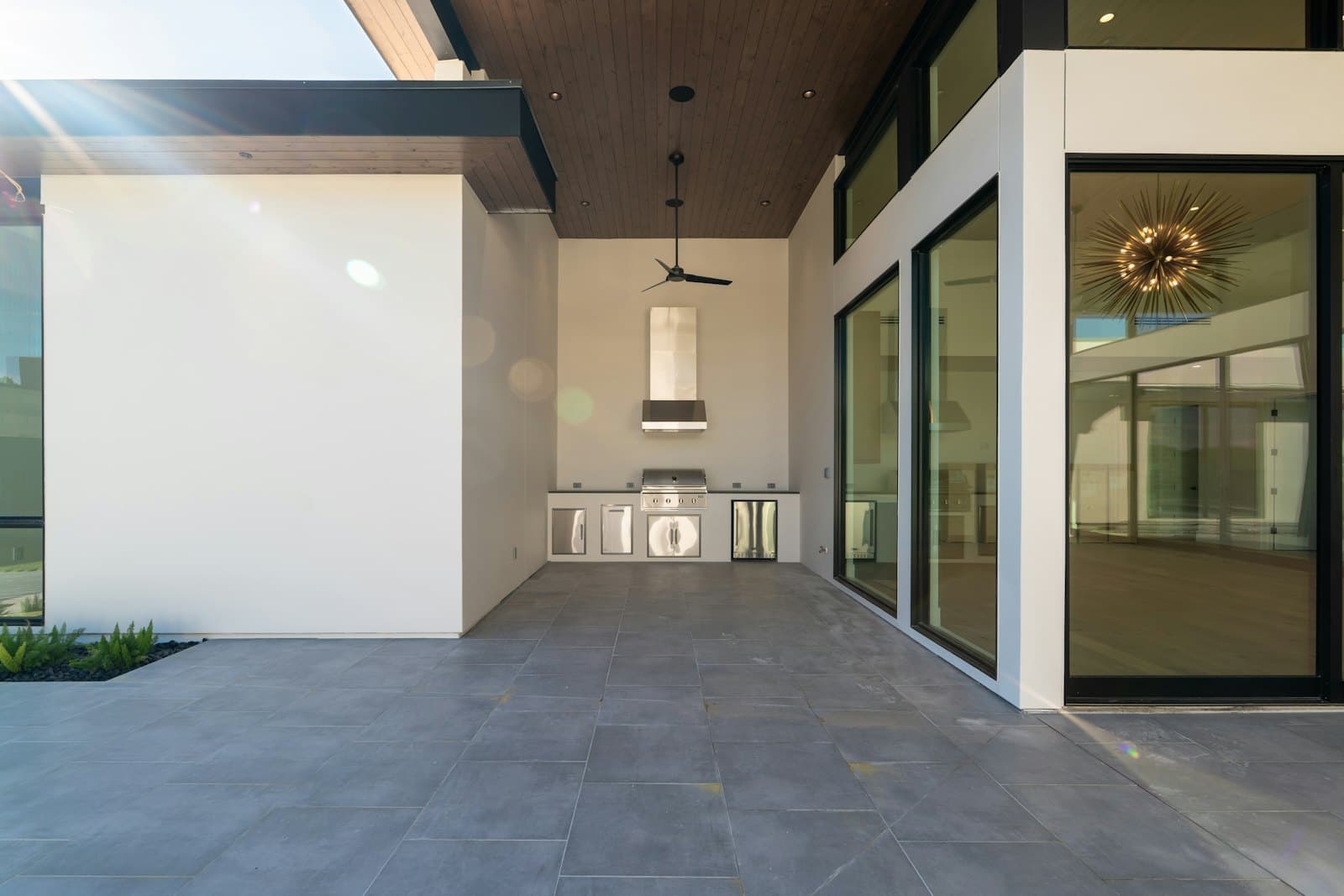 Covered outdoor kitchen beside glazed doors
