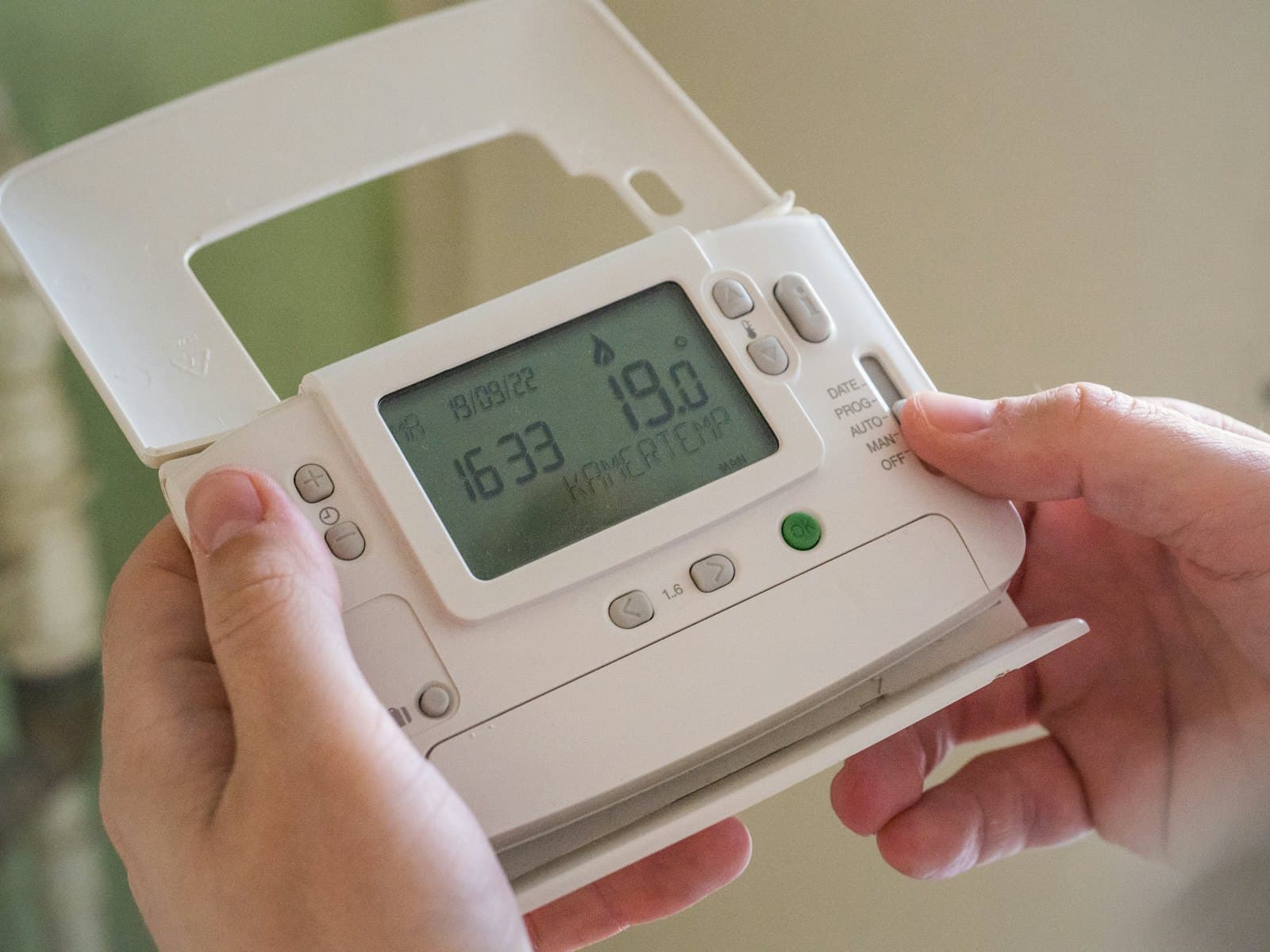 Hand holding a programmable heating thermostat